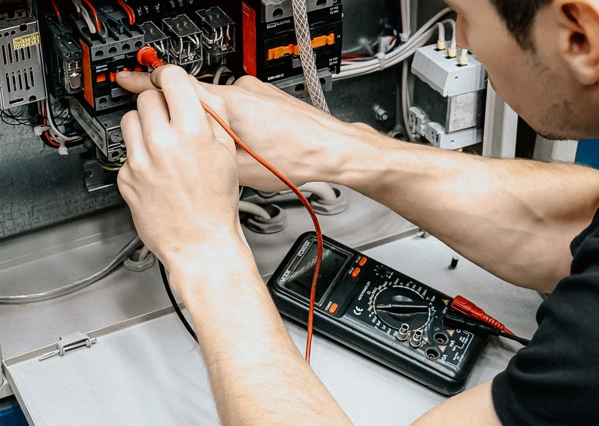Hands wiring the inside of an electrical control panel