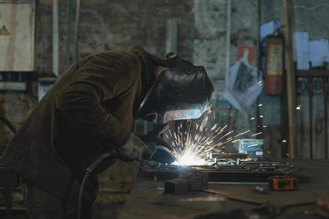 A welder at work in a workshop, sparks rising from the joint