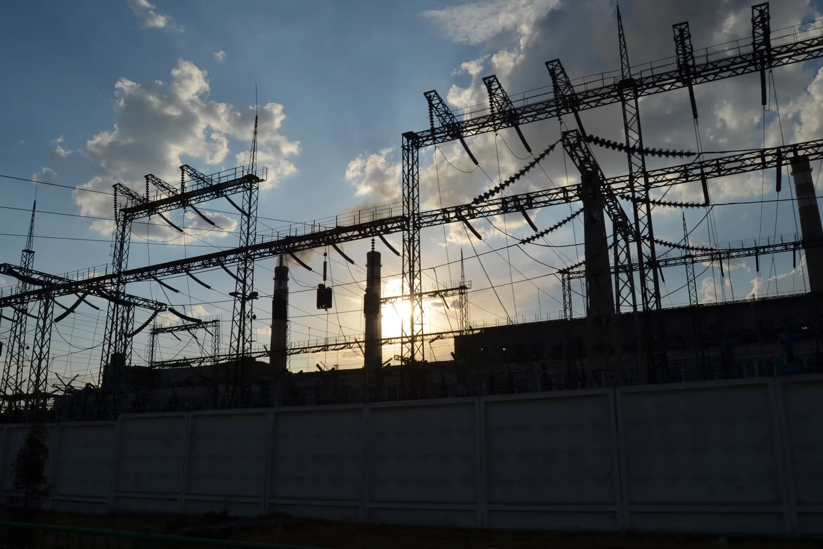 High-voltage substation yard against an evening sky